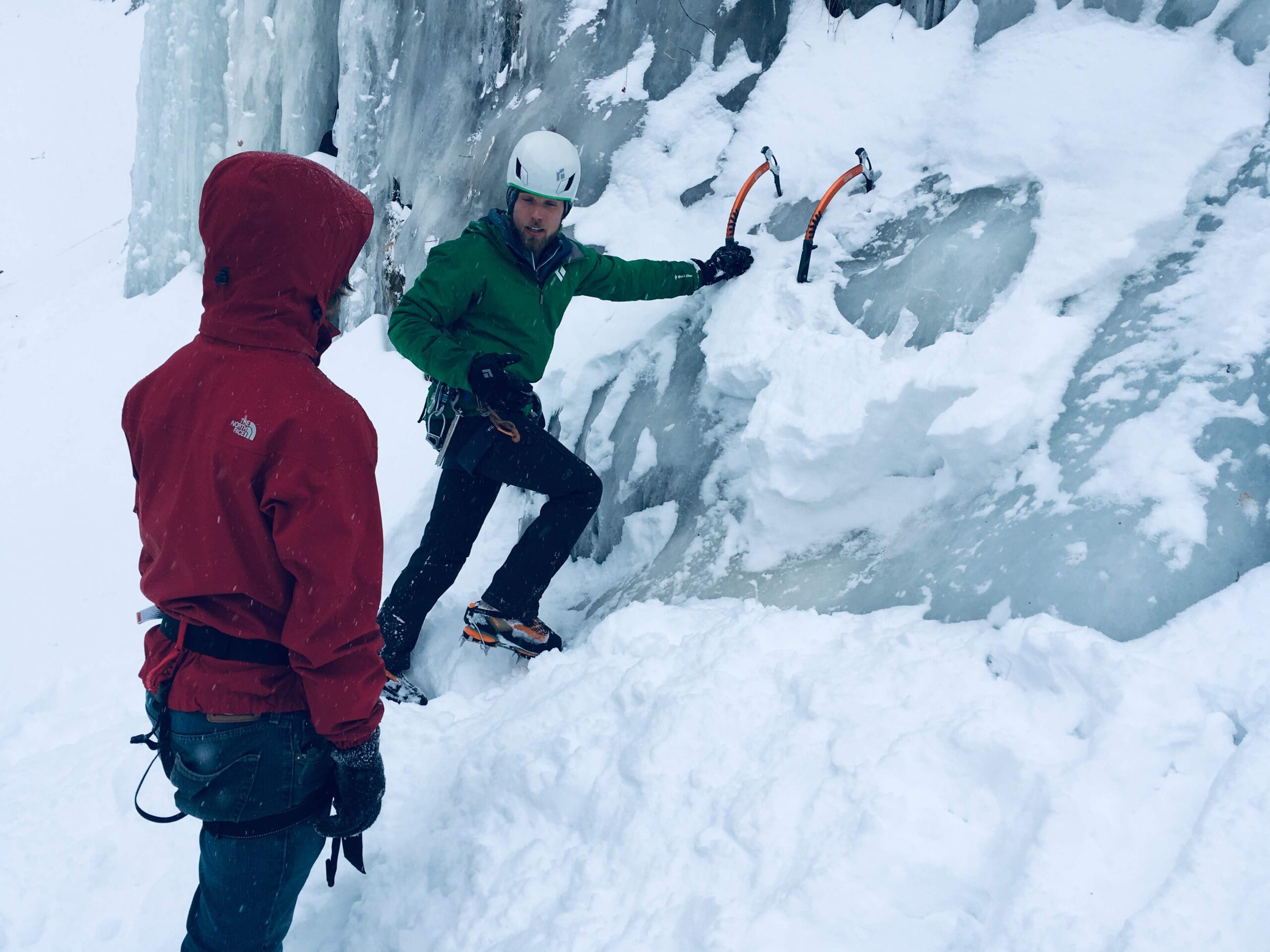 three Alpenists in winter climb rope on mountain. Travelers climb